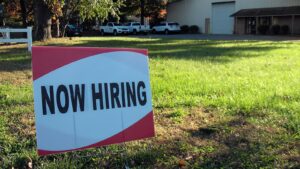 a now hiring sign in front of a building