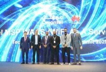 Seven men in business attire stand in front of a large digital display featuring the Omantel and Huawei logos at a technology summit.