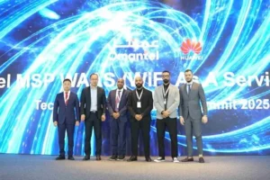 Seven men in business attire stand in front of a large digital display featuring the Omantel and Huawei logos at a technology summit.