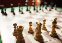 Close-up of white chess pieces on a chessboard, including a rook, knight, bishop, and pawns—symbolizing strategic ABM tactics for B2B brands in 2025—with black pieces blurred in the background.