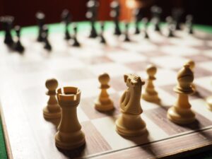 Close-up of white chess pieces on a chessboard, including a rook, knight, bishop, and pawns—symbolizing strategic ABM tactics for B2B brands in 2025—with black pieces blurred in the background.