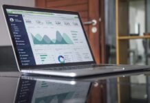 A laptop displays an analytics dashboard with charts, graphs, and data metrics on the screen—ideal for marketers tracking performance or avoiding lead qualification mistakes—situated on a reflective desk in an office setting.