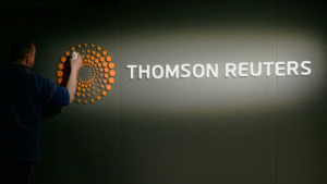 A person cleaning or adjusting the Thomson Reuters logo and sign on a dark wall, ensuring it looks sharp for their recent ABM overhaul.