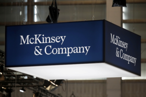 A large, blue and white McKinsey & Company sign hangs from the ceiling at an indoor event, where marketers discuss how to prove impact and address CEO-CMO misalignment.